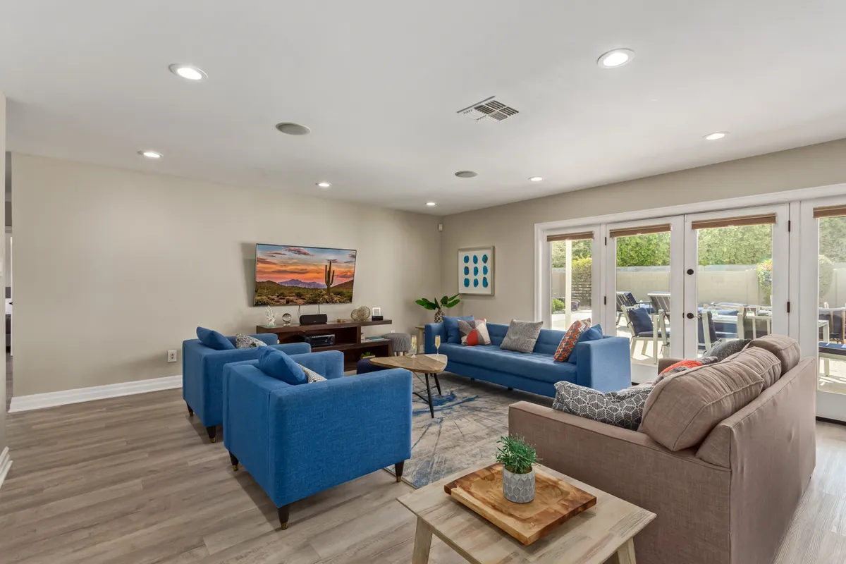 Another angle of a living area with blue sofas and a wooden coffee table, complemented by large windows and wall art. The space exudes comfort and warmth, ideal for family reunions, entertaining friends, or relaxing after a day outdoors.
