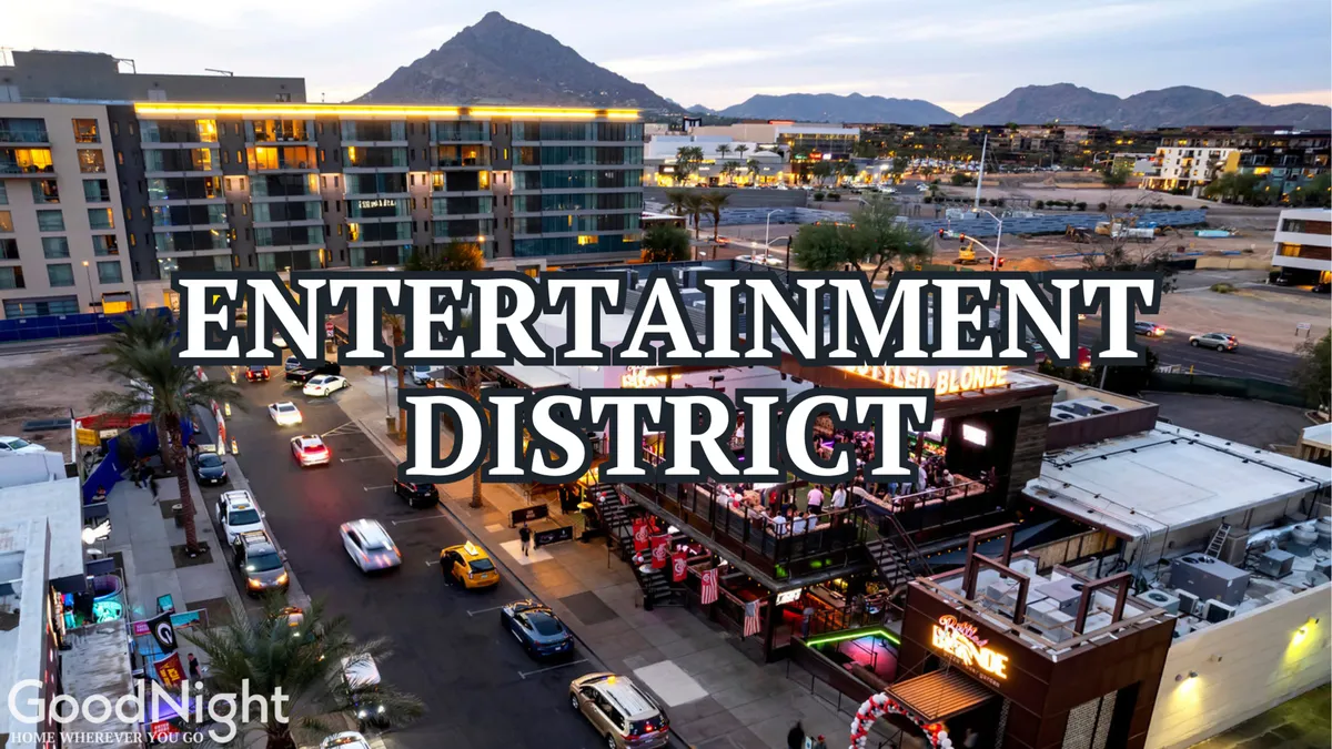 A bustling exterior scene showcasing the vibrant entertainment district signage, a busy street lined with cars, lively outdoor dining areas, and the silhouette of mountains in the background. The energy of nightlife and dining is apparent, with people enjoying the dynamic urban atmosphere.