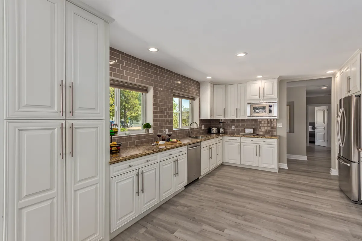 A welcoming kitchen with a large island, stainless steel appliances, granite countertops, and a window view. The spacious layout is perfect for preparing group meals, hosting celebrations, and accessing starter kitchen essentials provided for guests.