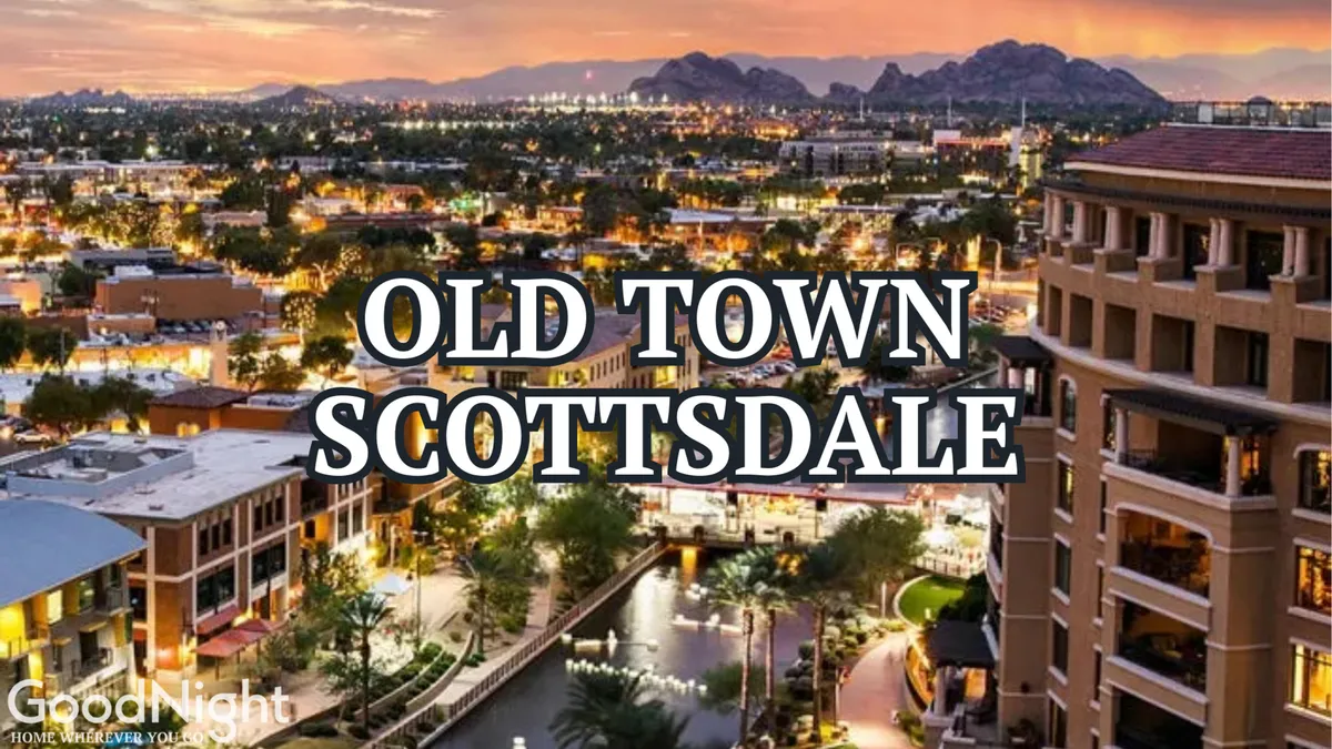 A lively evening scene showcasing Scottsdale’s city skyline with illuminated buildings, a waterway lined with palm trees, and mountains in the background. Street lights reflect across the water, and people are seen enjoying evening strolls along the waterfront.